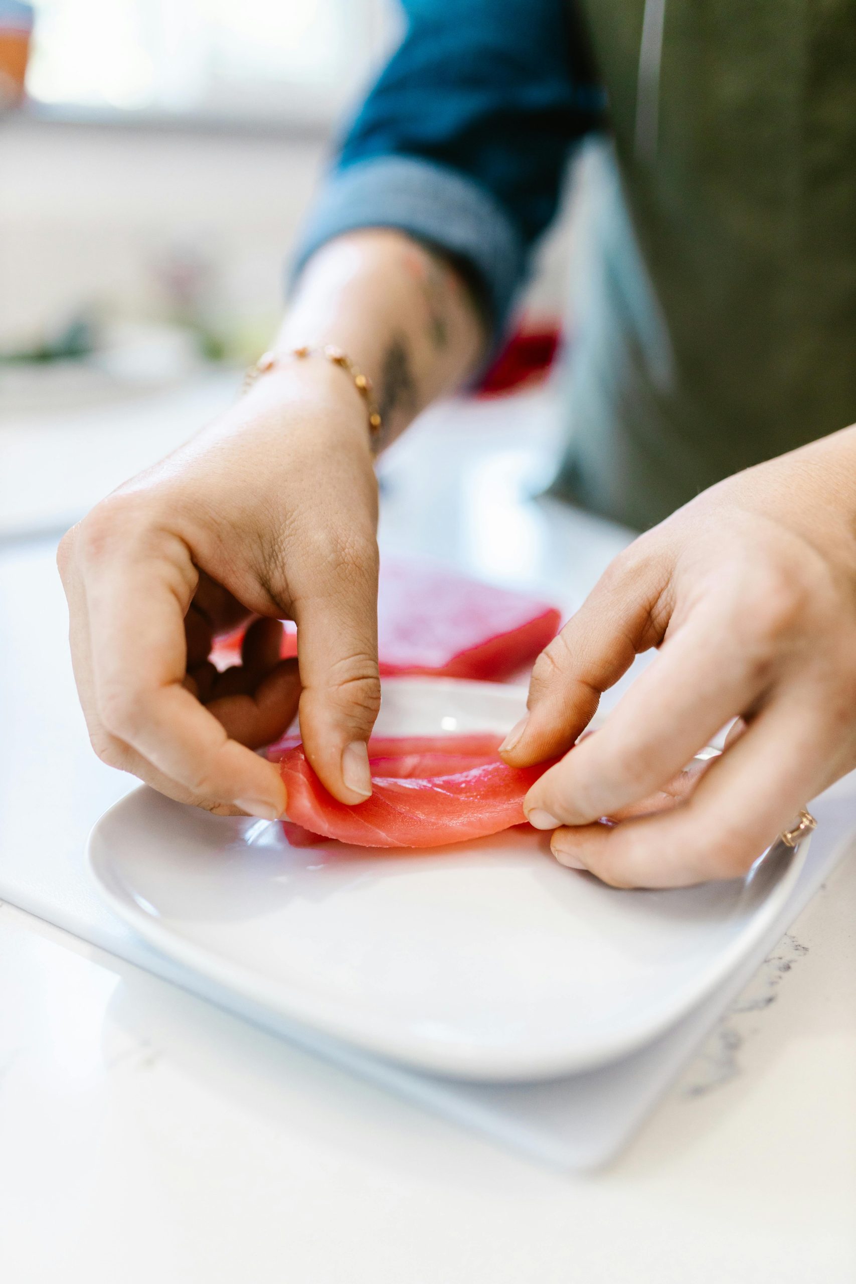 Close-up of hands preparing fresh sashimi, showcasing culinary artistry.